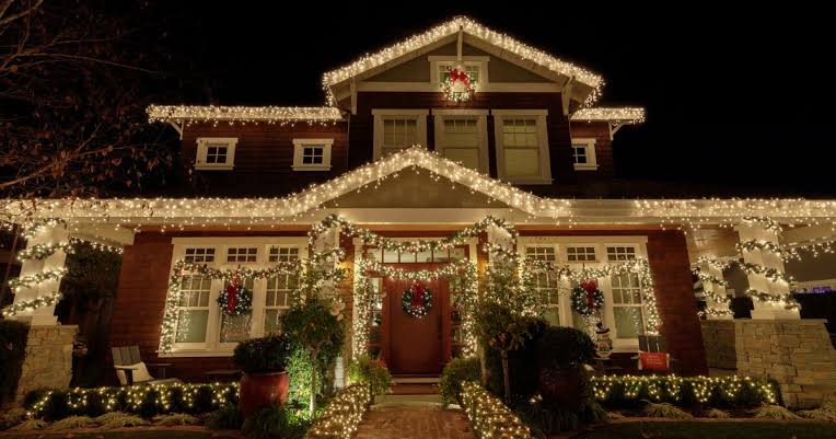Warm-white icicle lighting and garland installed along a roofline and entryway