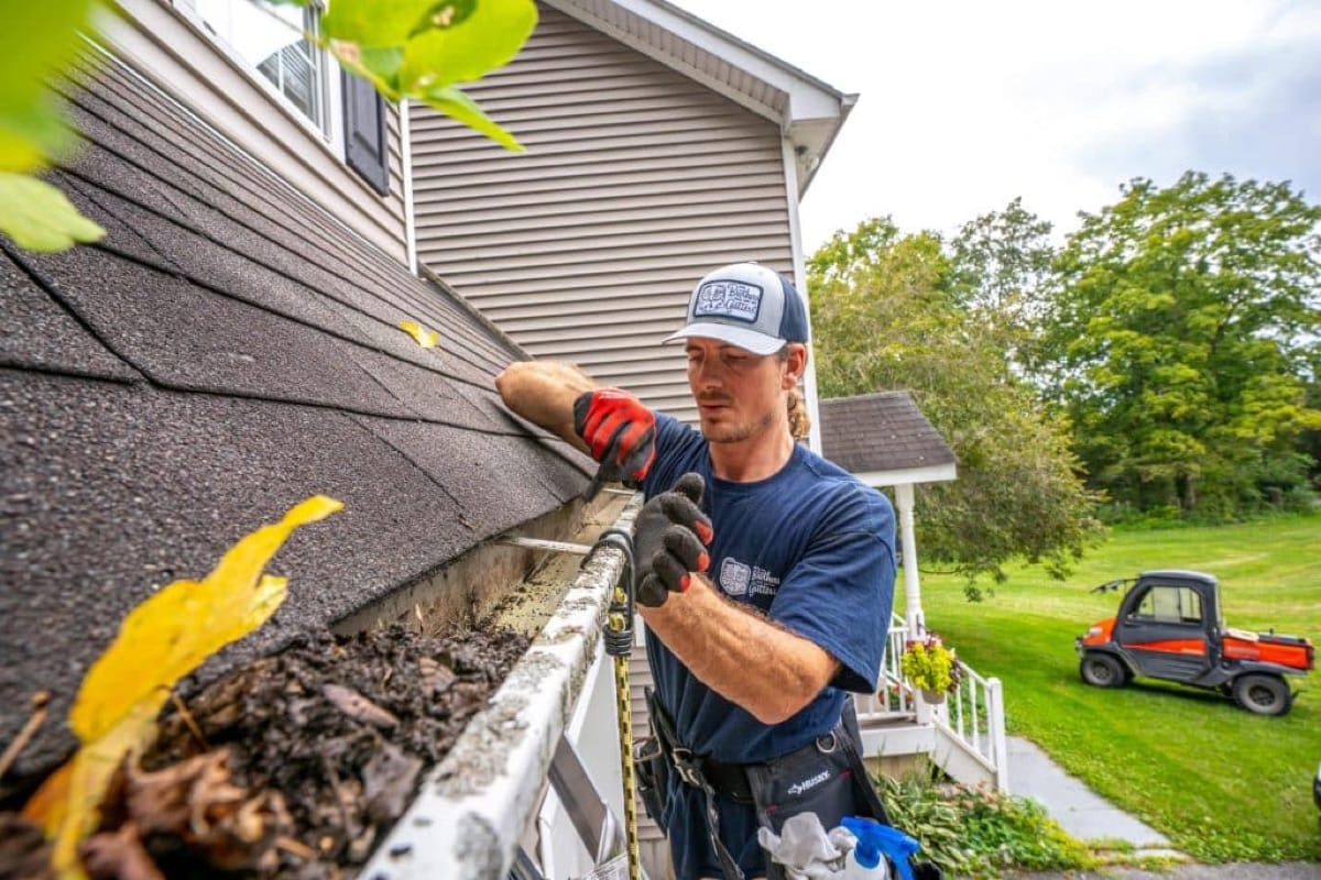 Technician clearing debris from a gutter