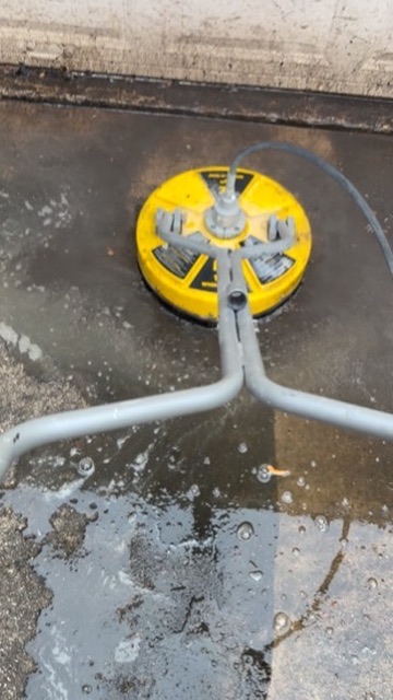 Yellow surface cleaner rinsing a driveway